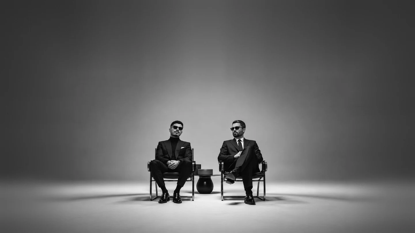 Os sócios da Habitat, Bruno Quadros e Emanuel Henrique, sentados lado a lado em poltronas, em foto preto e branco.